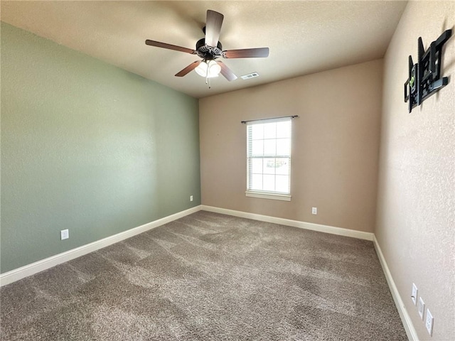 carpeted empty room with baseboards, a ceiling fan, visible vents, and a textured wall