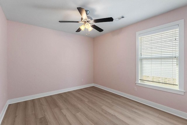 empty room with a ceiling fan, visible vents, light wood-style flooring, and baseboards