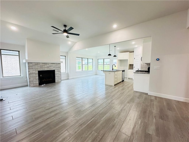 6405 NW Harley St, Bentonville, AR 72713 - unfurnished living room with light wood-style flooring, ceiling fan, a fireplace, lofted ceiling, and recessed lighting