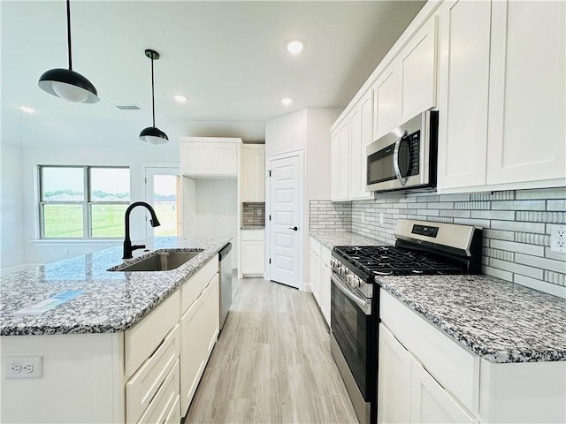 6405 NW Harley St, Bentonville, AR 72713 - kitchen featuring appliances with stainless steel finishes, light wood-style flooring, backsplash, white cabinetry, and light stone countertops