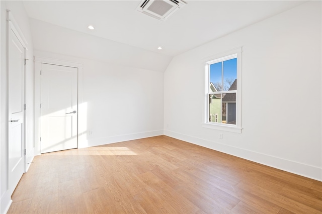 unfurnished room featuring light wood finished floors, baseboards, lofted ceiling, and visible vents