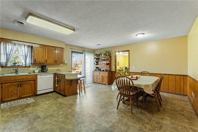 304 Angela St, Springdale, AR 72762 - kitchen featuring brown cabinetry, a peninsula, a healthy amount of sunlight, dishwasher, and a sink