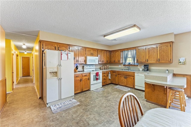 304 Angela St, Springdale, AR 72762 - kitchen with white appliances, a peninsula, light countertops, a sink, and brown cabinets