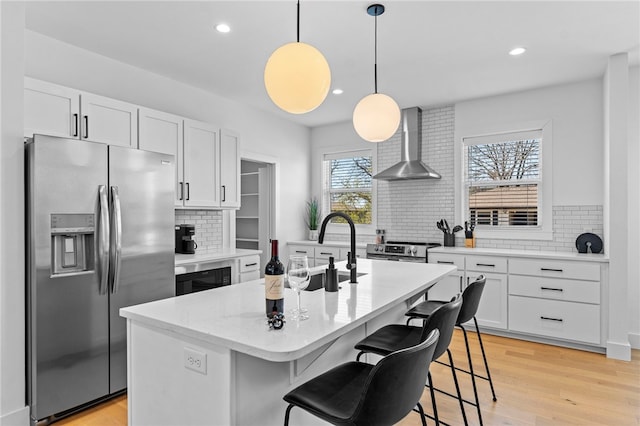 kitchen with wall chimney exhaust hood, backsplash, white cabinetry, and appliances with stainless steel finishes