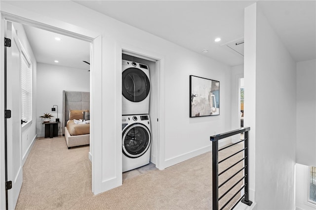 clothes washing area with laundry area, stacked washer and dryer, recessed lighting, attic access, and light carpet