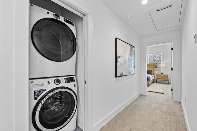 washroom with baseboards, stacked washer / dryer, laundry area, carpet floors, and attic access