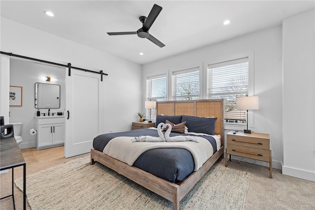 bedroom with ensuite bathroom, baseboards, recessed lighting, and a barn door