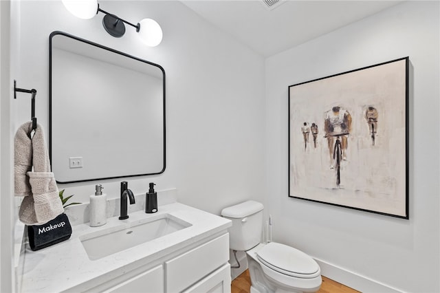 bathroom featuring toilet, vanity, and wood finished floors