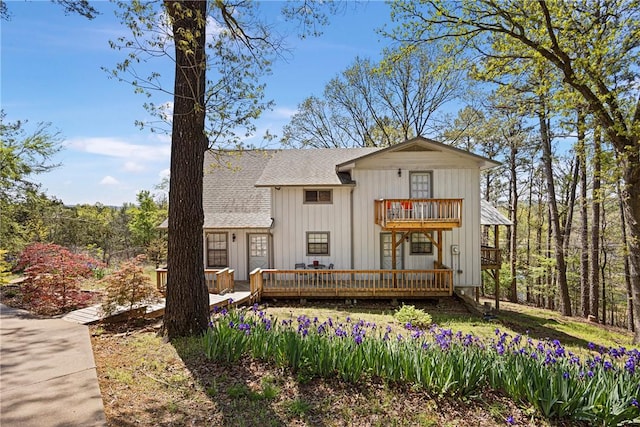 view of front facade featuring board and batten siding, a shingled roof, a wooden deck, and a balcony