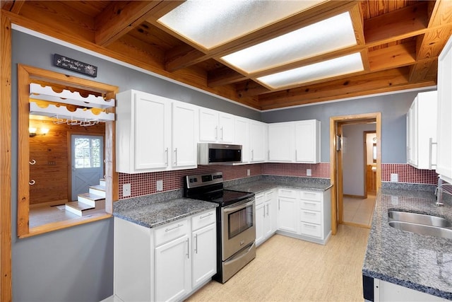 kitchen with white cabinets, decorative backsplash, a sink, and appliances with stainless steel finishes