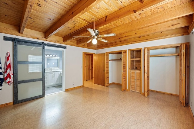 unfurnished bedroom with beamed ceiling, a barn door, wood ceiling, multiple closets, and baseboards