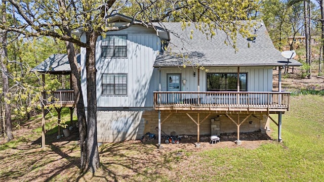 back of property featuring roof with shingles, a yard, and a wooden deck