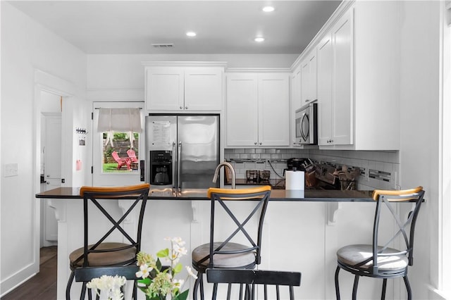 328 Martin Luther King Jr Blvd, Fayetteville, AR 72701 - kitchen featuring stainless steel appliances, dark countertops, decorative backsplash, a kitchen bar, and recessed lighting