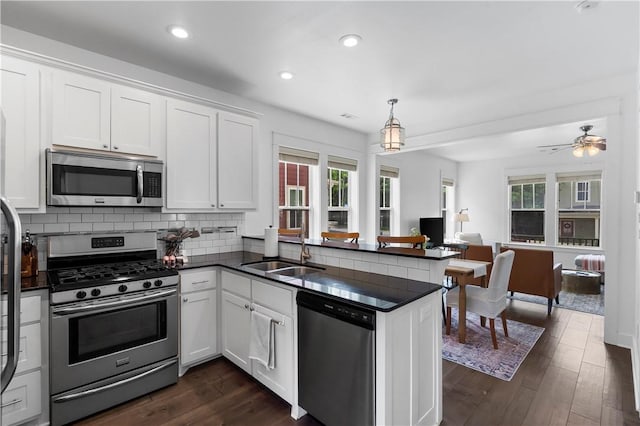 328 Martin Luther King Jr Blvd, Fayetteville, AR 72701 - kitchen featuring appliances with stainless steel finishes, dark countertops, open floor plan, a peninsula, and white cabinets