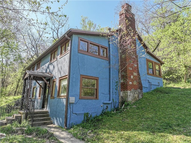 view of home's exterior featuring a yard, a chimney, and stucco siding