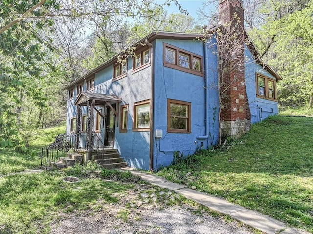 view of front of home with stucco siding, a chimney, and a front yard