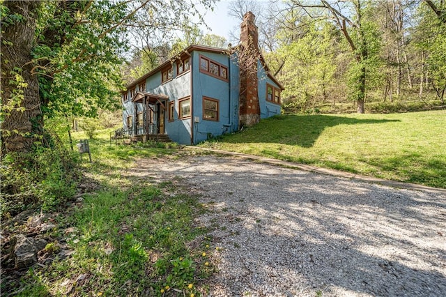 view of property exterior with a chimney, a yard, and stucco siding