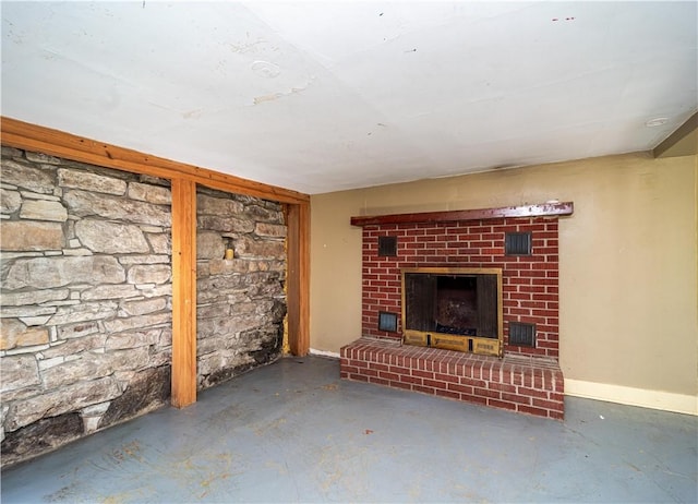 unfurnished living room featuring concrete flooring, a fireplace, and baseboards
