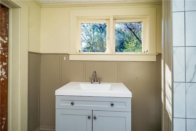 bathroom with a decorative wall, vanity, and ornamental molding