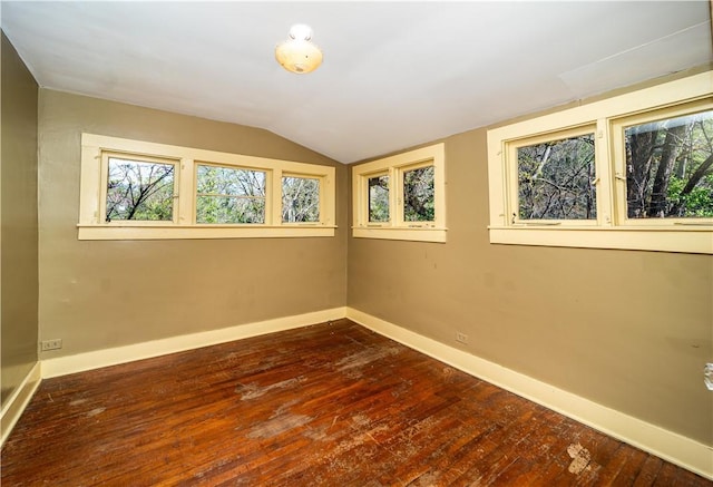 spare room featuring dark wood-type flooring, lofted ceiling, a wealth of natural light, and baseboards