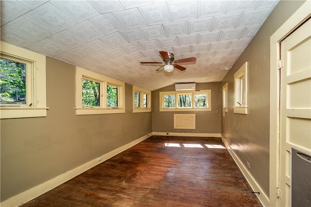 unfurnished room featuring an AC wall unit, baseboards, lofted ceiling, wood finished floors, and ceiling fan