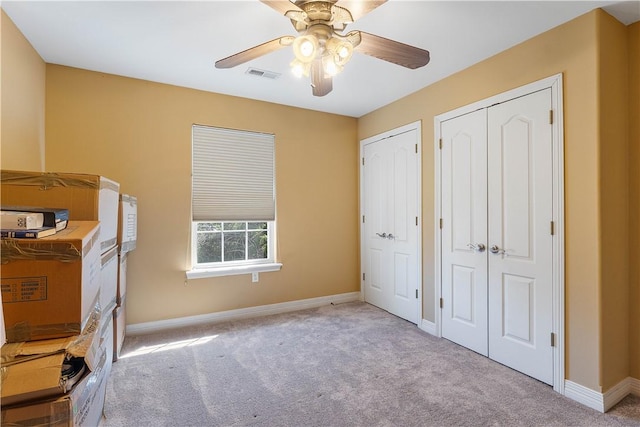 unfurnished bedroom with baseboards, multiple closets, visible vents, and carpet floors