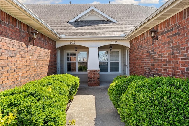 doorway to property with brick siding and roof with shingles