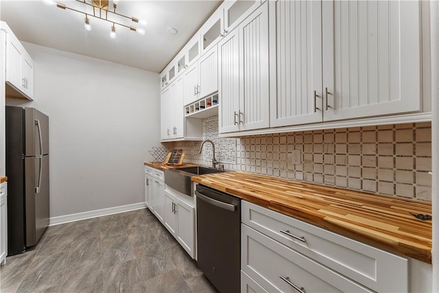kitchen featuring tasteful backsplash, baseboards, a sink, appliances with stainless steel finishes, and wood counters