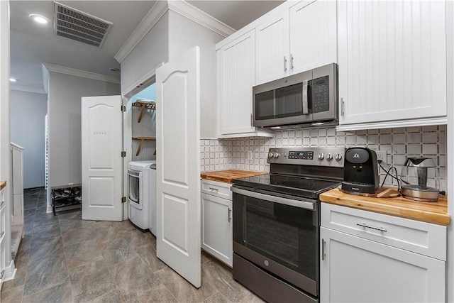 kitchen with butcher block counters, ornamental molding, visible vents, and stainless steel appliances