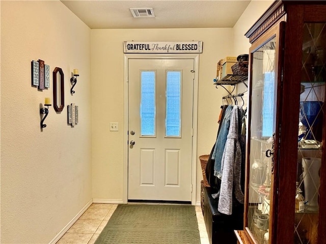 doorway to outside with visible vents, baseboards, and light tile patterned flooring