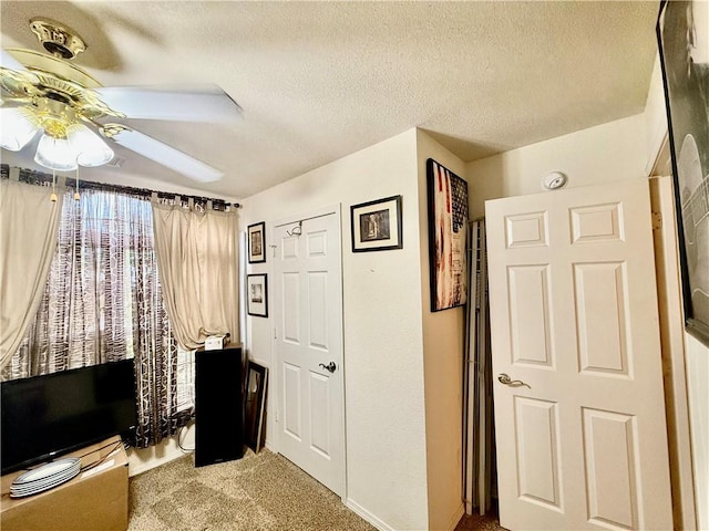 interior space featuring a textured ceiling, carpet flooring, and ceiling fan
