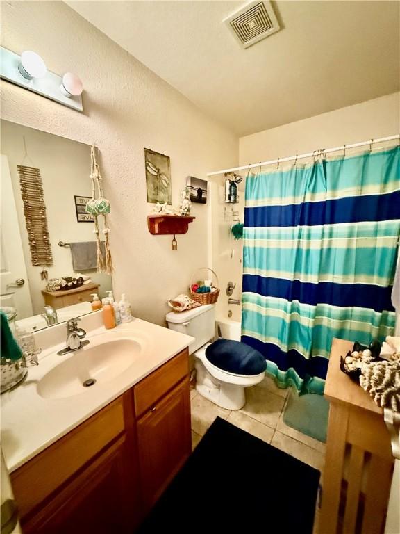 bathroom featuring vanity, visible vents, toilet, curtained shower, and tile patterned floors