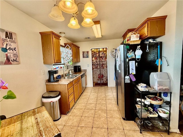 kitchen with brown cabinets, light tile patterned flooring, a sink, and stainless steel appliances