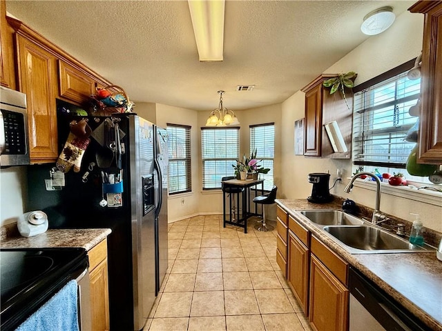 kitchen with a chandelier, appliances with stainless steel finishes, a sink, and a wealth of natural light