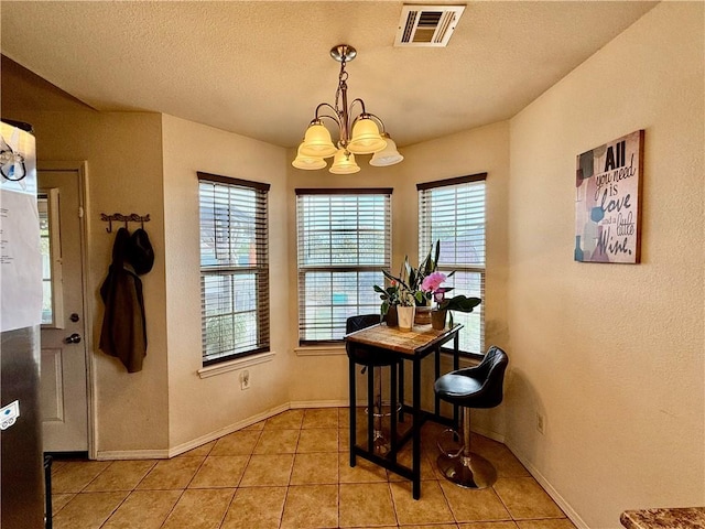 dining space with a wealth of natural light, light tile patterned floors, visible vents, and an inviting chandelier