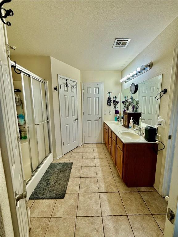 full bath featuring a sink, tile patterned flooring, and a stall shower