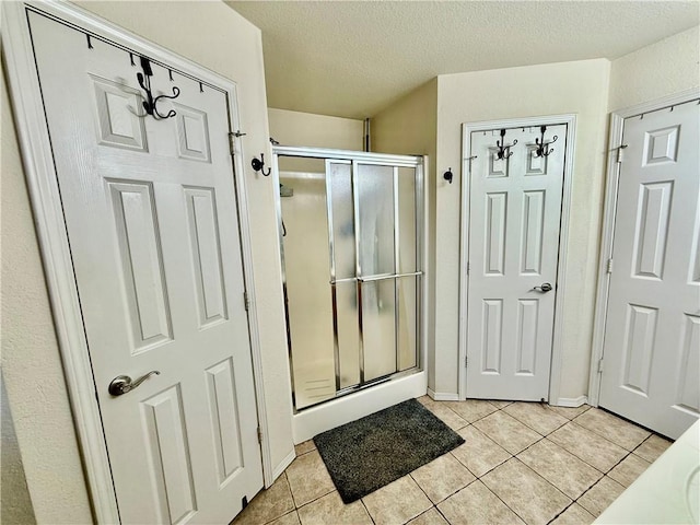 full bathroom featuring tile patterned floors, a stall shower, and a textured ceiling