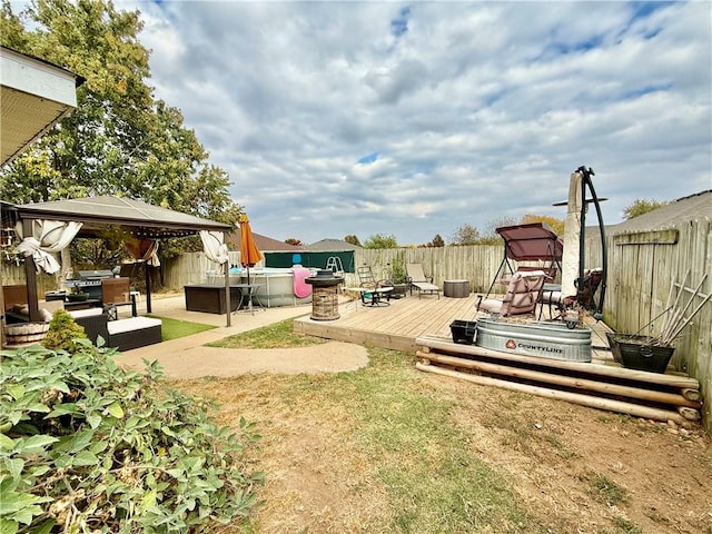 view of yard featuring a gazebo, a fenced backyard, a wooden deck, and an outdoor living space with a fire pit