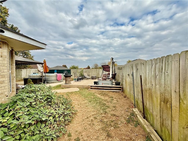 view of yard with a jacuzzi, a fenced backyard, and a wooden deck
