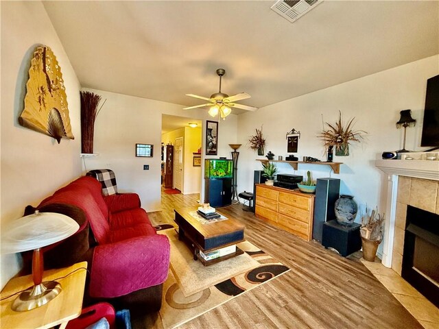 living room featuring visible vents, ceiling fan, wood finished floors, and a fireplace