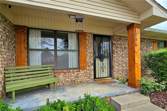 property entrance featuring brick siding and covered porch