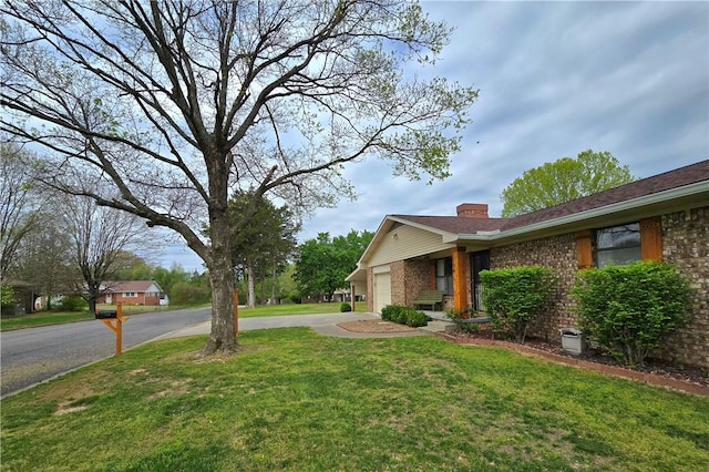 view of yard with aphalt driveway and a garage