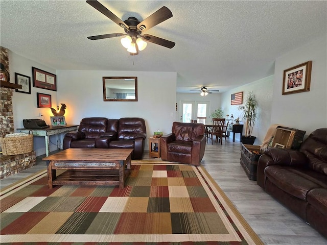 living room featuring a textured ceiling, wood finished floors, and ceiling fan