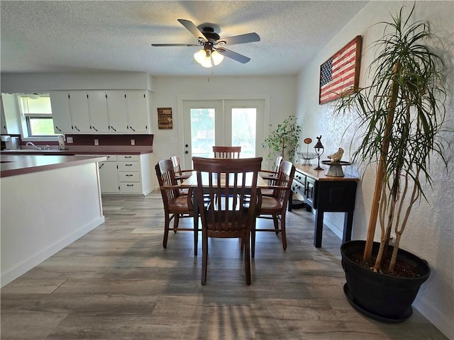 dining space featuring a textured ceiling, wood finished floors, ceiling fan, and baseboards