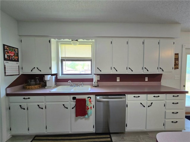 kitchen featuring a sink, stainless steel dishwasher, white cabinetry, and a textured ceiling