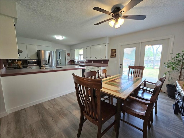 dining space featuring a textured ceiling, wood finished floors, and a ceiling fan