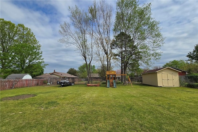 view of yard featuring a shed, a fenced backyard, a playground, and an outdoor structure