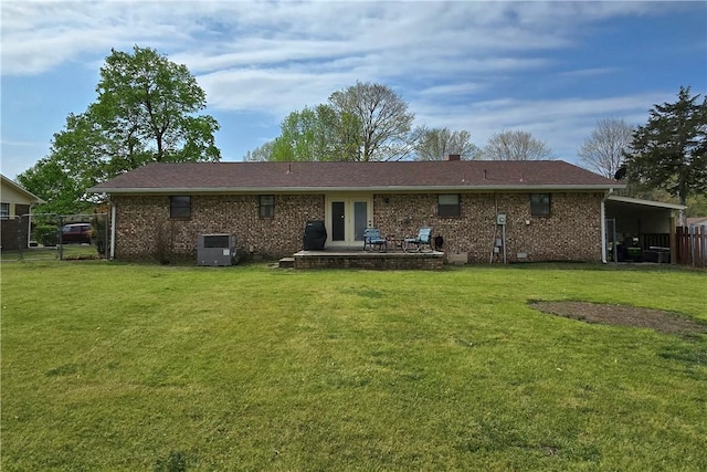 rear view of property featuring a yard, french doors, fence, and brick siding