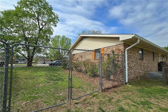 view of side of property featuring brick siding, fence, and a lawn
