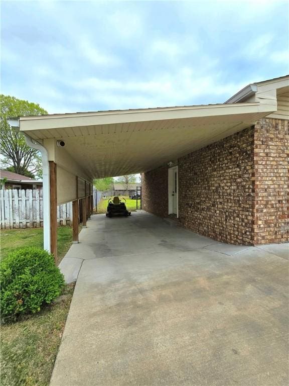 view of vehicle parking with an attached carport, driveway, and fence